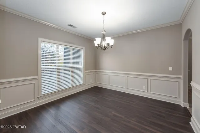 an empty room with wooden floor a kitchen view and a kitchen