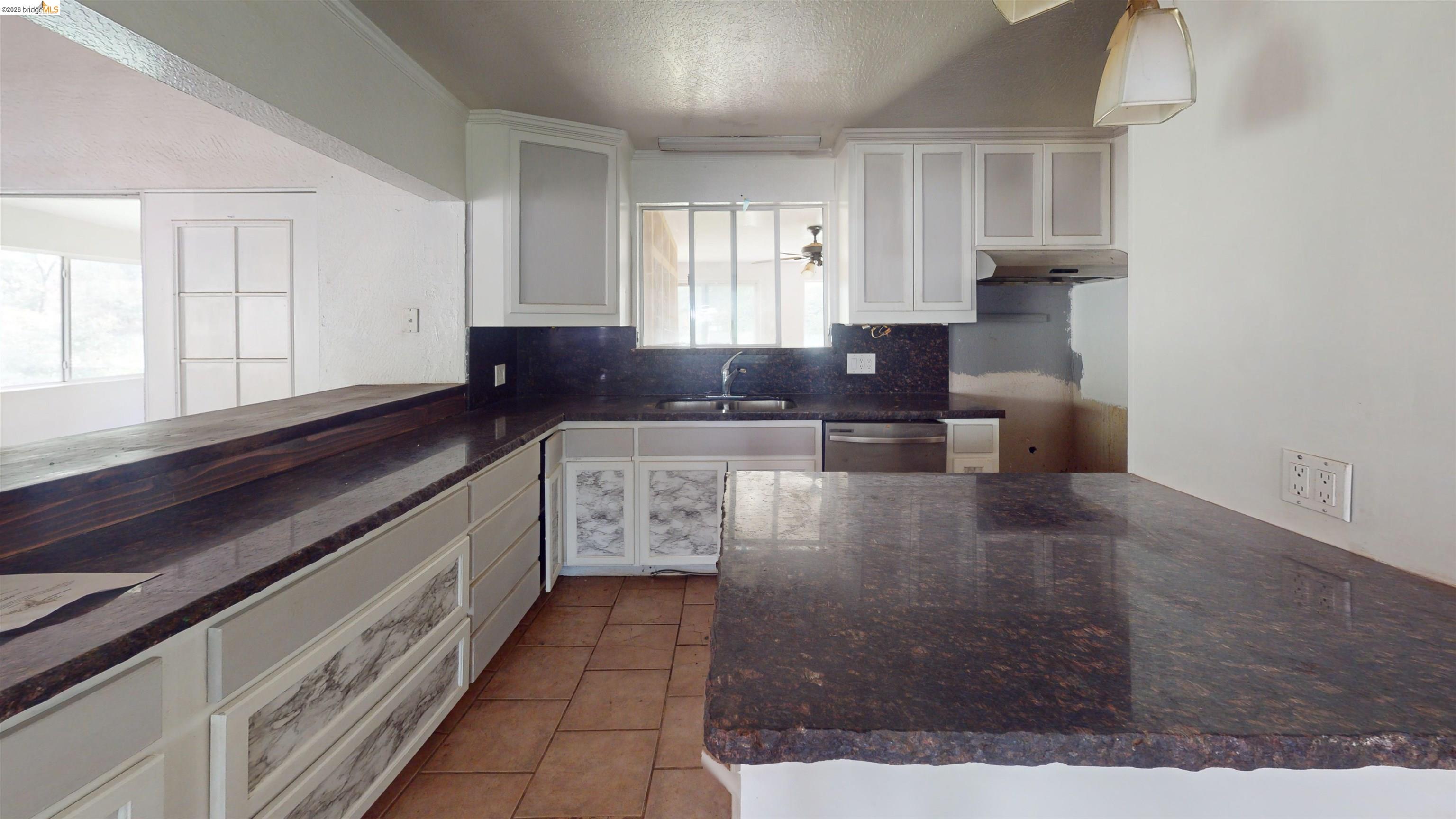 20231 Hidden Acres Road Sonora, CA 95370 - Photo 12 of 25 Kitchen featuring white cabinetry, dark stone countertops, tile flooring, and an integrated dishwasher