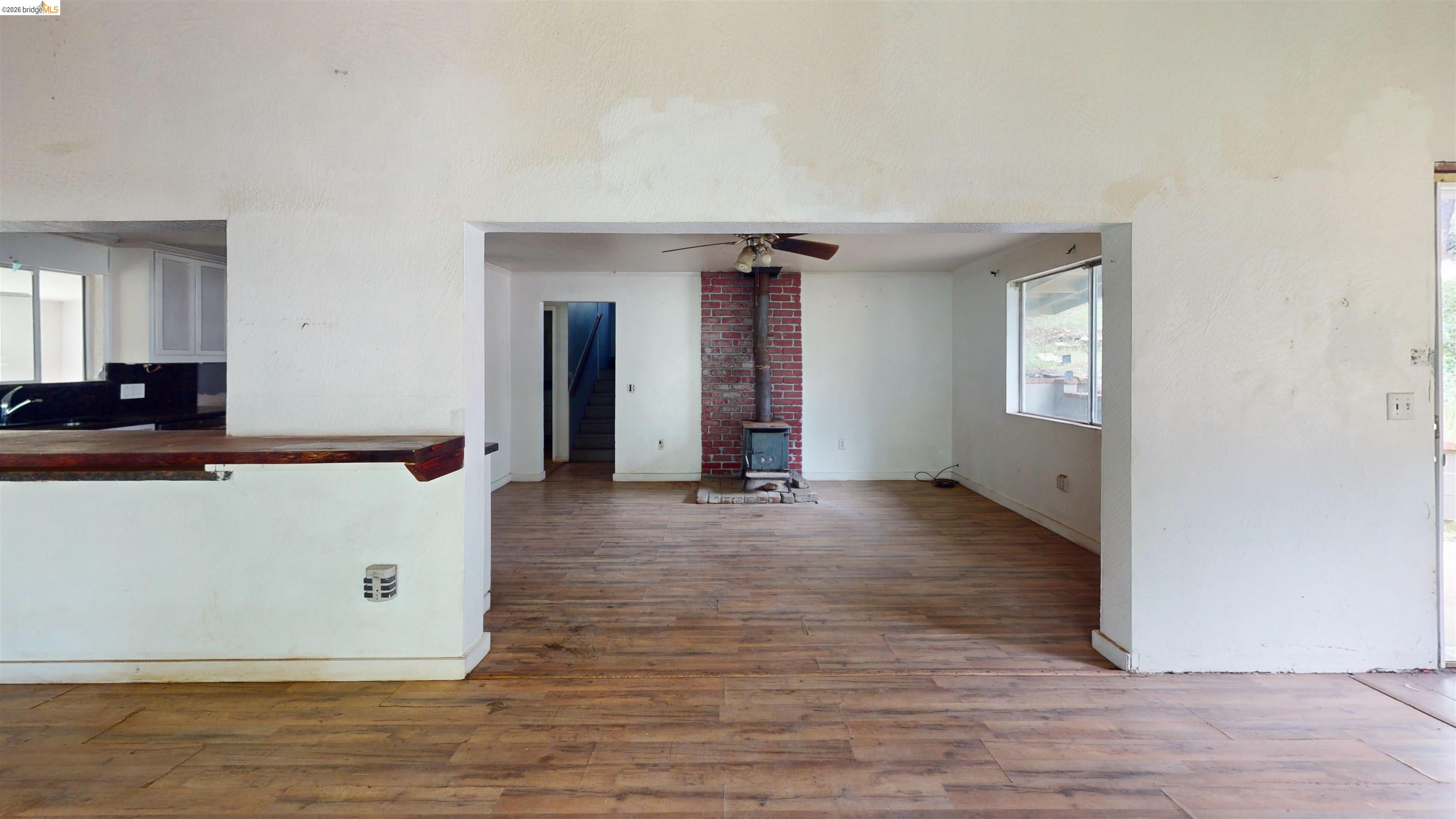 20231 Hidden Acres Road Sonora, CA 95370 - Photo 15 of 25 Open concept living area featuring wood-finish flooring, a brick fireplace with a wood-burning stove, and ample natural light from a large window