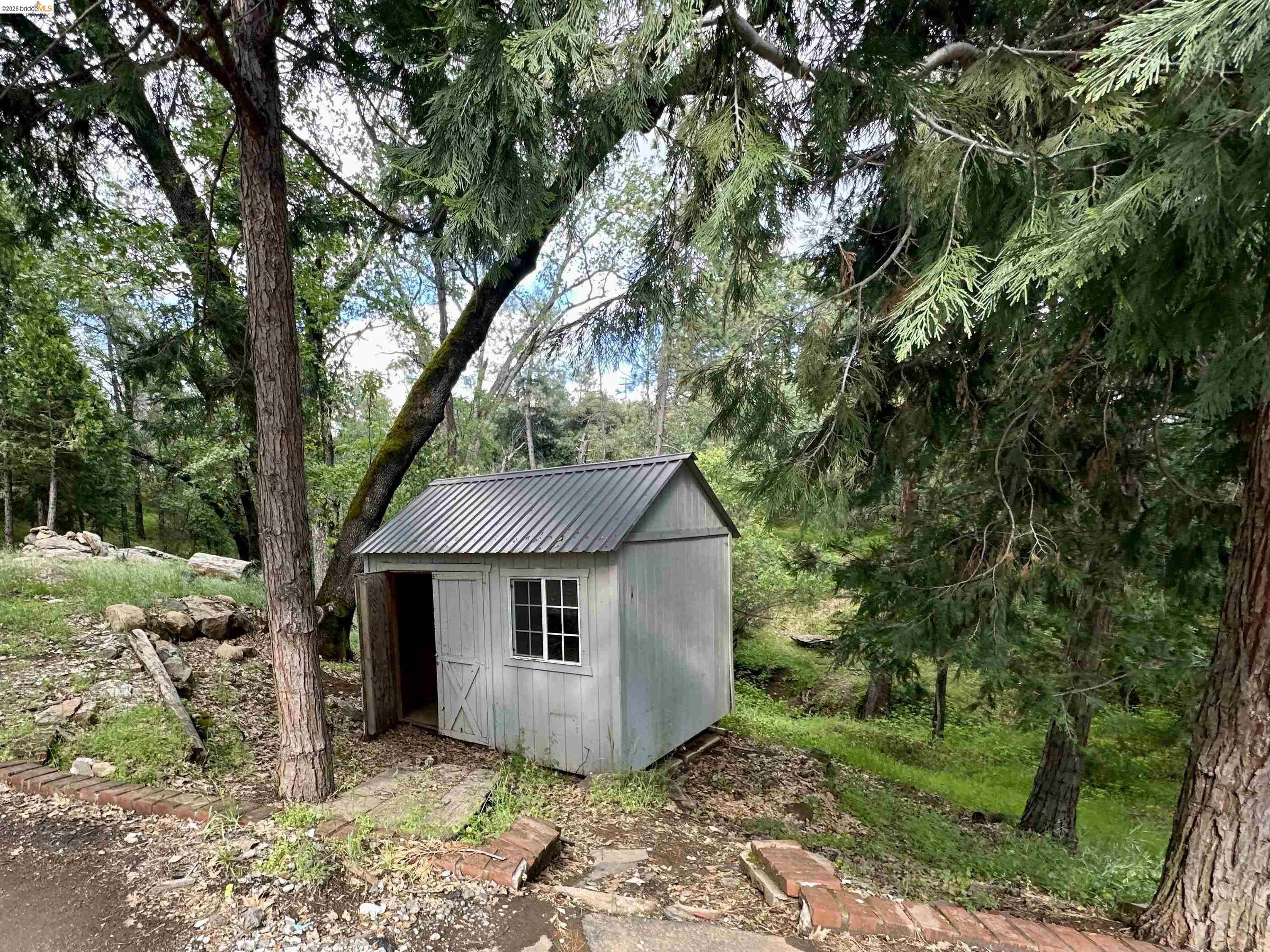 20231 Hidden Acres Road Sonora, CA 95370 - Photo 25 of 25 White wood-sided shed featuring a corrugated metal roof and a single-pane window