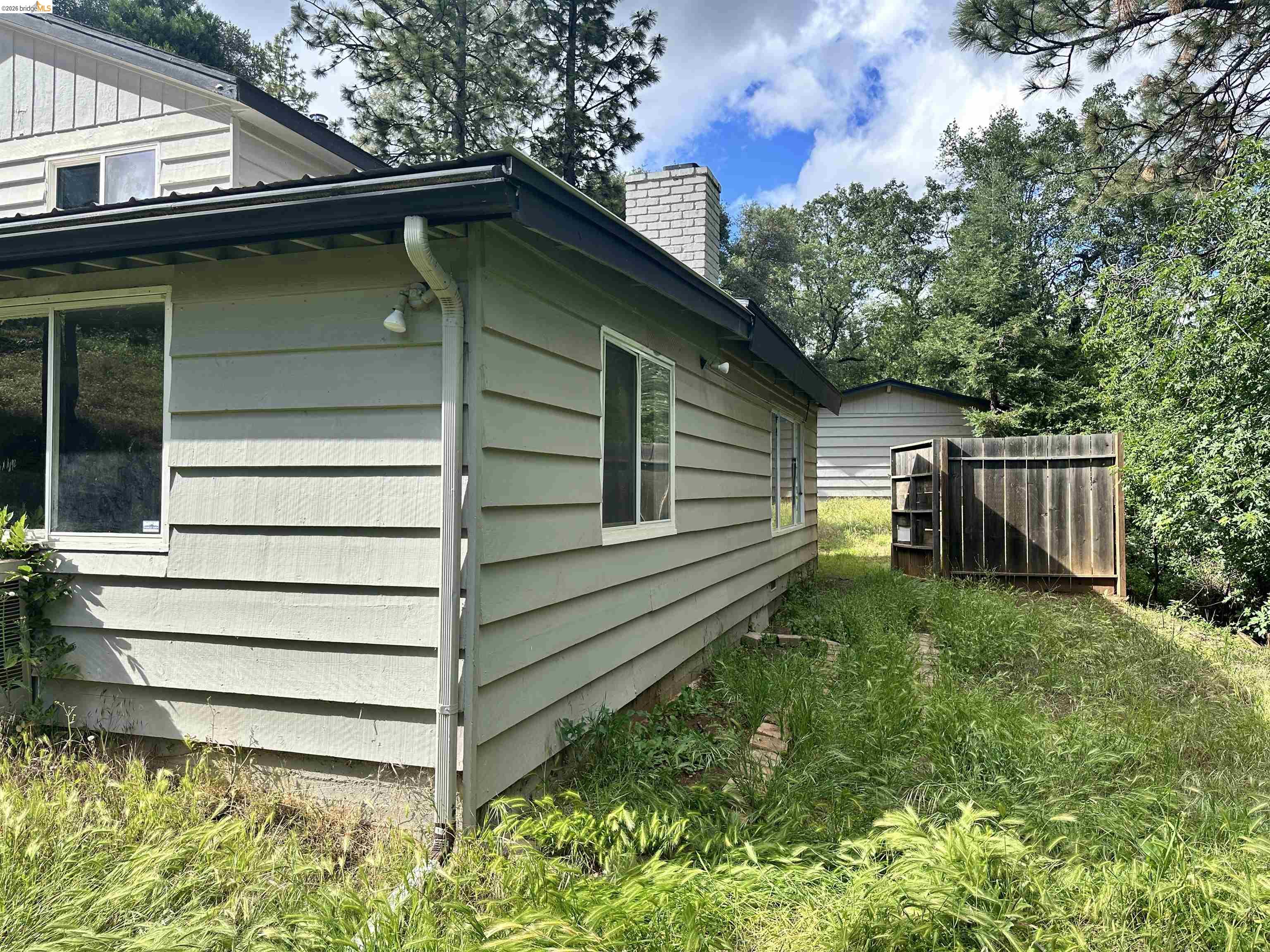 20231 Hidden Acres Road Sonora, CA 95370 - Photo 4 of 25 Exterior siding with white trim windows and a dark roofline