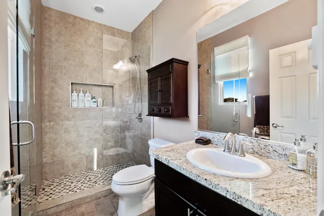a bathroom with a granite countertop sink toilet a large mirror and shower