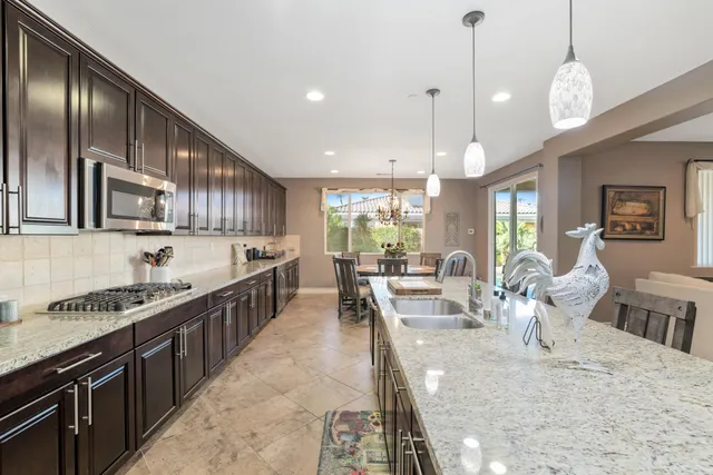 a large kitchen with stainless steel appliances kitchen island granite countertop a large counter top a stove a chimney a sink and a dining table