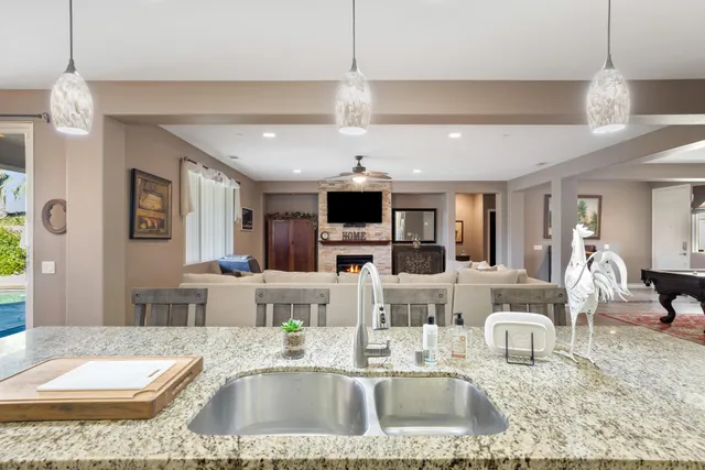 a large living room with stainless steel appliances kitchen island granite countertop a couch and a coffee table