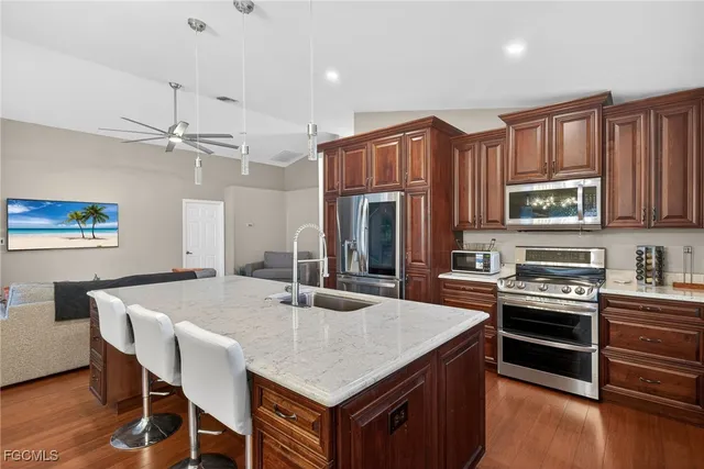 a kitchen with stainless steel appliances granite countertop a stove a refrigerator a kitchen island a sink dishwasher and white cabinets with wooden floor