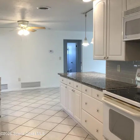 a kitchen with granite countertop white cabinets and stainless steel appliances