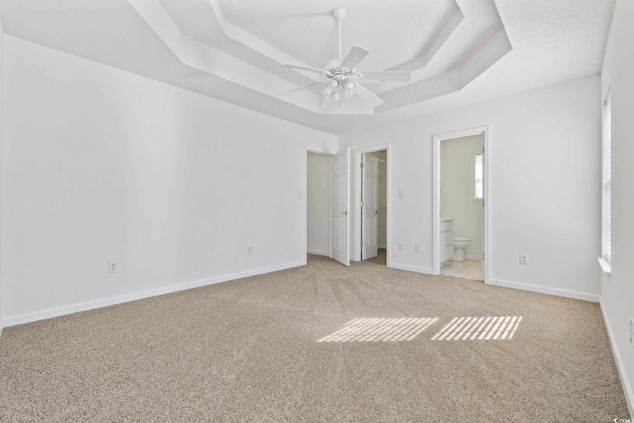 133 Marsh Rabbit Drive Myrtle Beach, SC 29588 - Photo 20 of 33 Unfurnished bedroom featuring a raised ceiling, a walk in closet, light colored carpet, a ceiling fan, and ensuite bathroom