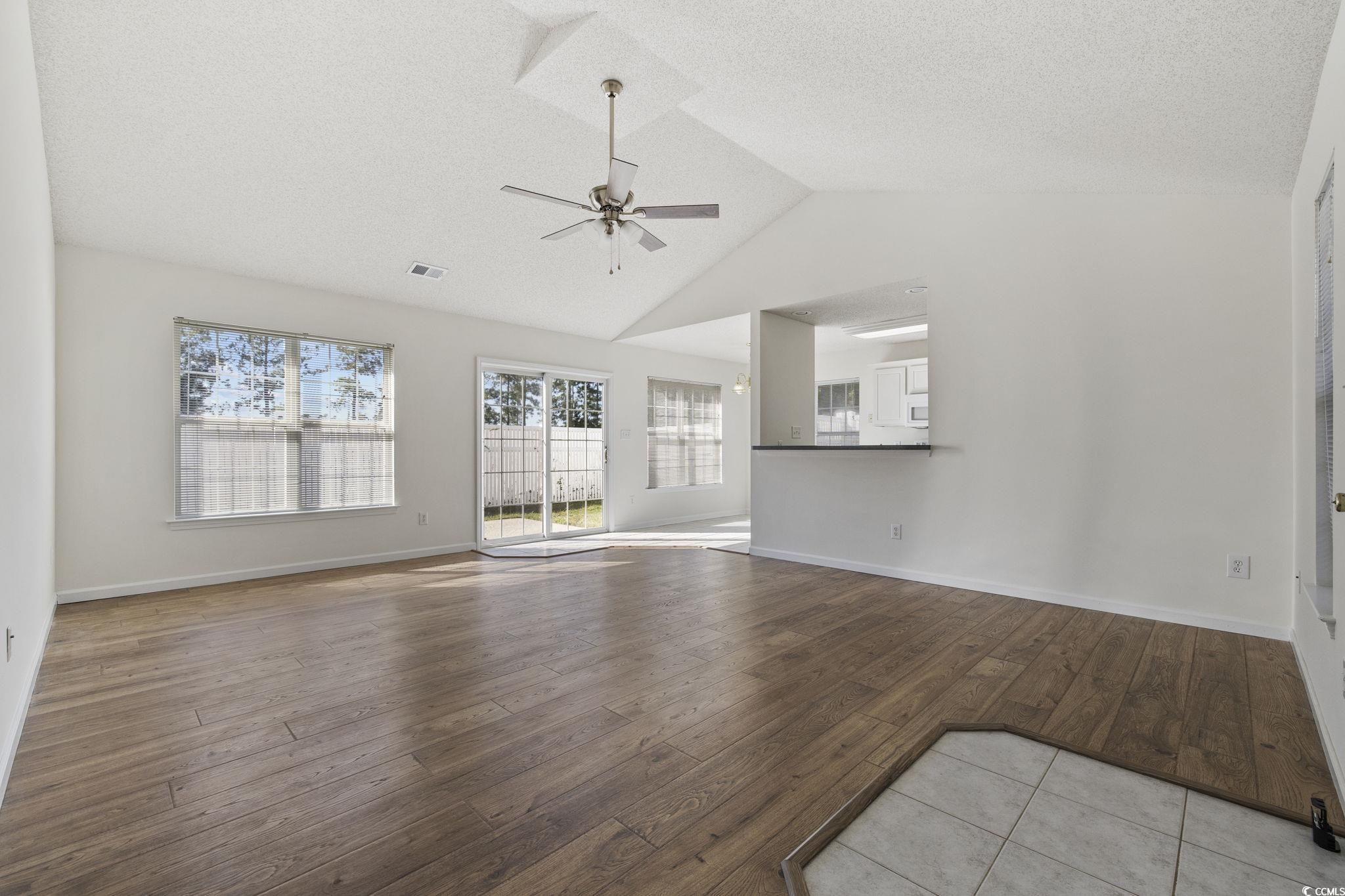 133 Marsh Rabbit Drive Myrtle Beach, SC 29588 - Photo 6 of 33 Unfurnished living room featuring vaulted ceiling, hardwood / wood-style floors, a textured ceiling, and a ceiling fan