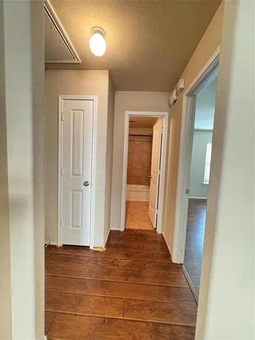 a view of a hallway with wooden floor and cabinet