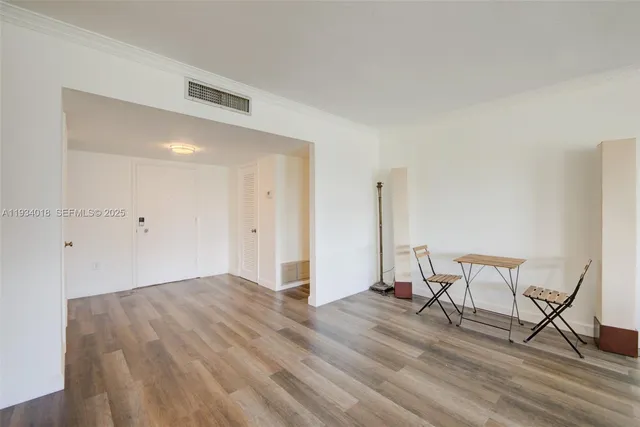 a view of an empty room with wooden floor and closet