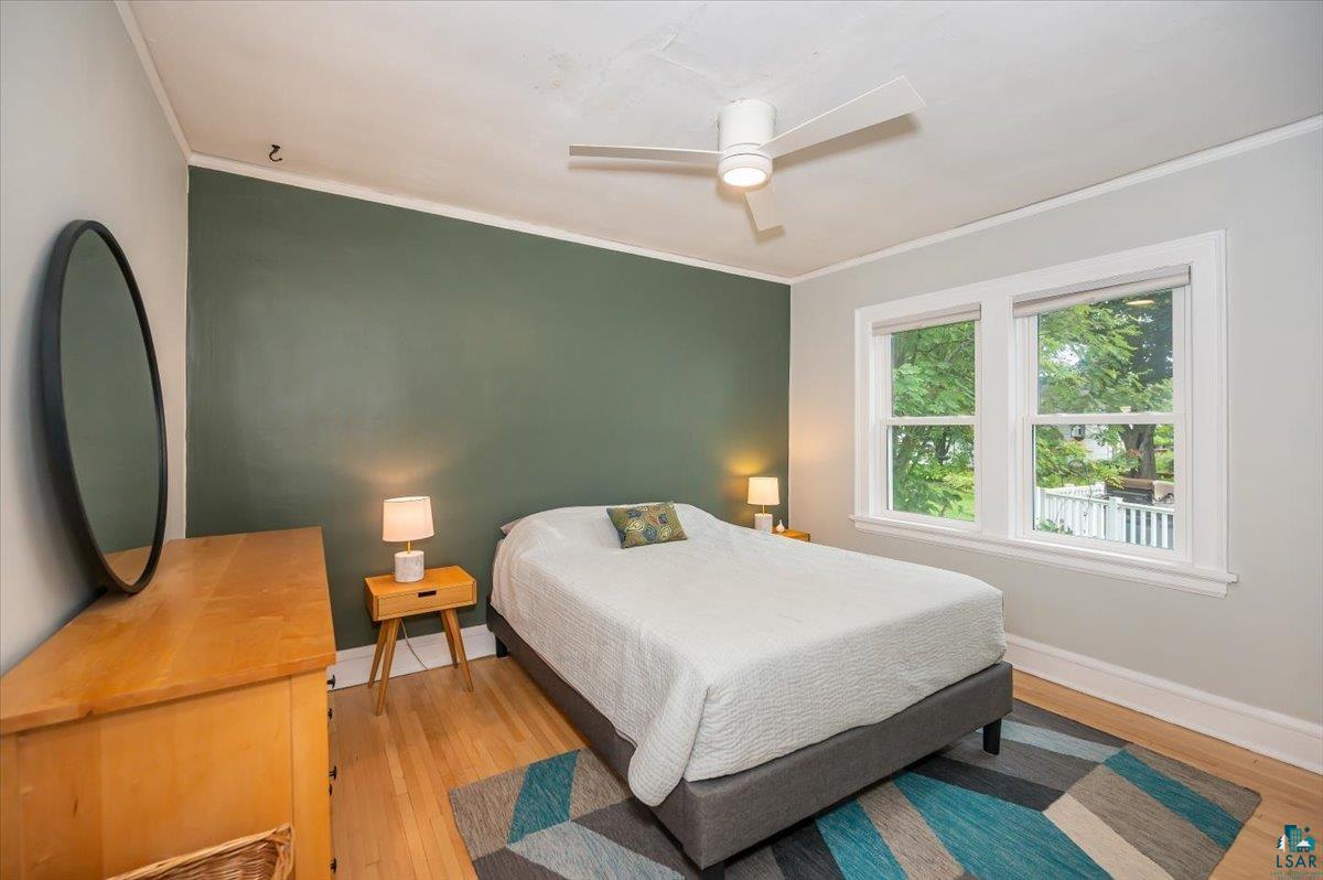5401 Otsego Street Duluth, MN 55804 - Photo 15 of 36 Room featuring a decorative accent wall, wood-finish flooring, white trim, and a ceiling fan with integrated lighting