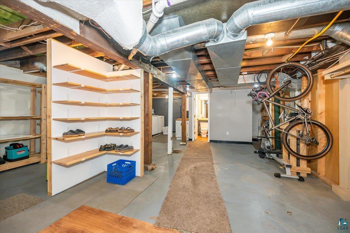 5401 Otsego Street Duluth, MN 55804 - Photo 17 of 36 Finished basement space featuring exposed ceiling joists and ductwork, L-shaped built-in shelving, concrete flooring, and an additional storage area