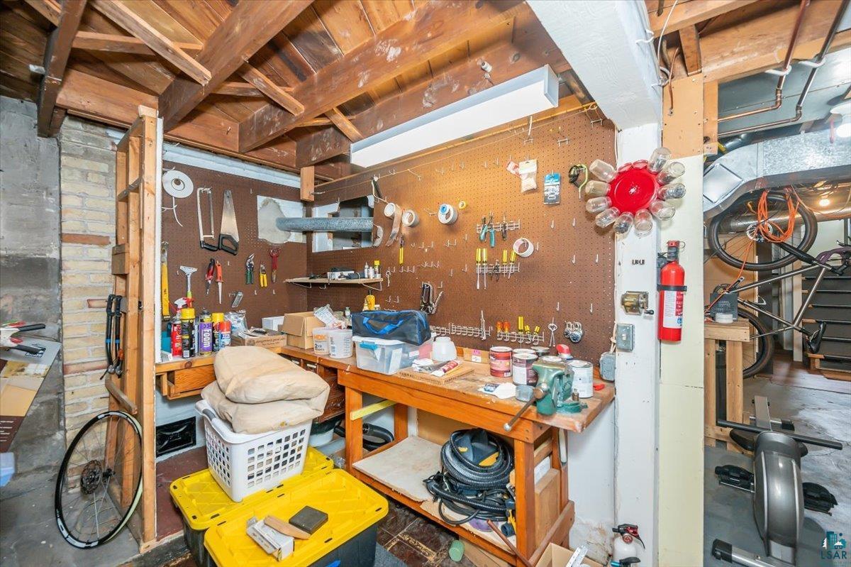 5401 Otsego Street Duluth, MN 55804 - Photo 23 of 36 Basement workspace featuring exposed wooden ceiling beams and a functional pegboard organization system