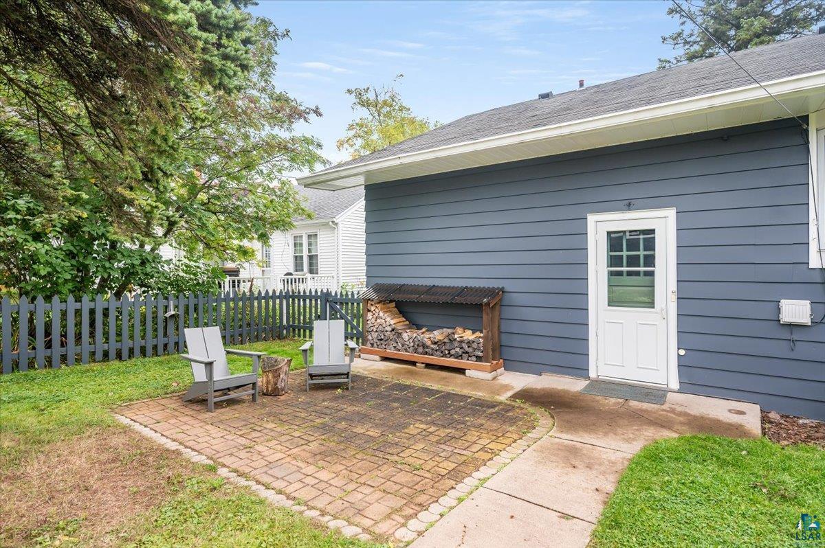 5401 Otsego Street Duluth, MN 55804 - Photo 25 of 36 Exterior featuring blue horizontal siding, a white paneled door with windowpanes, and a brick paver patio