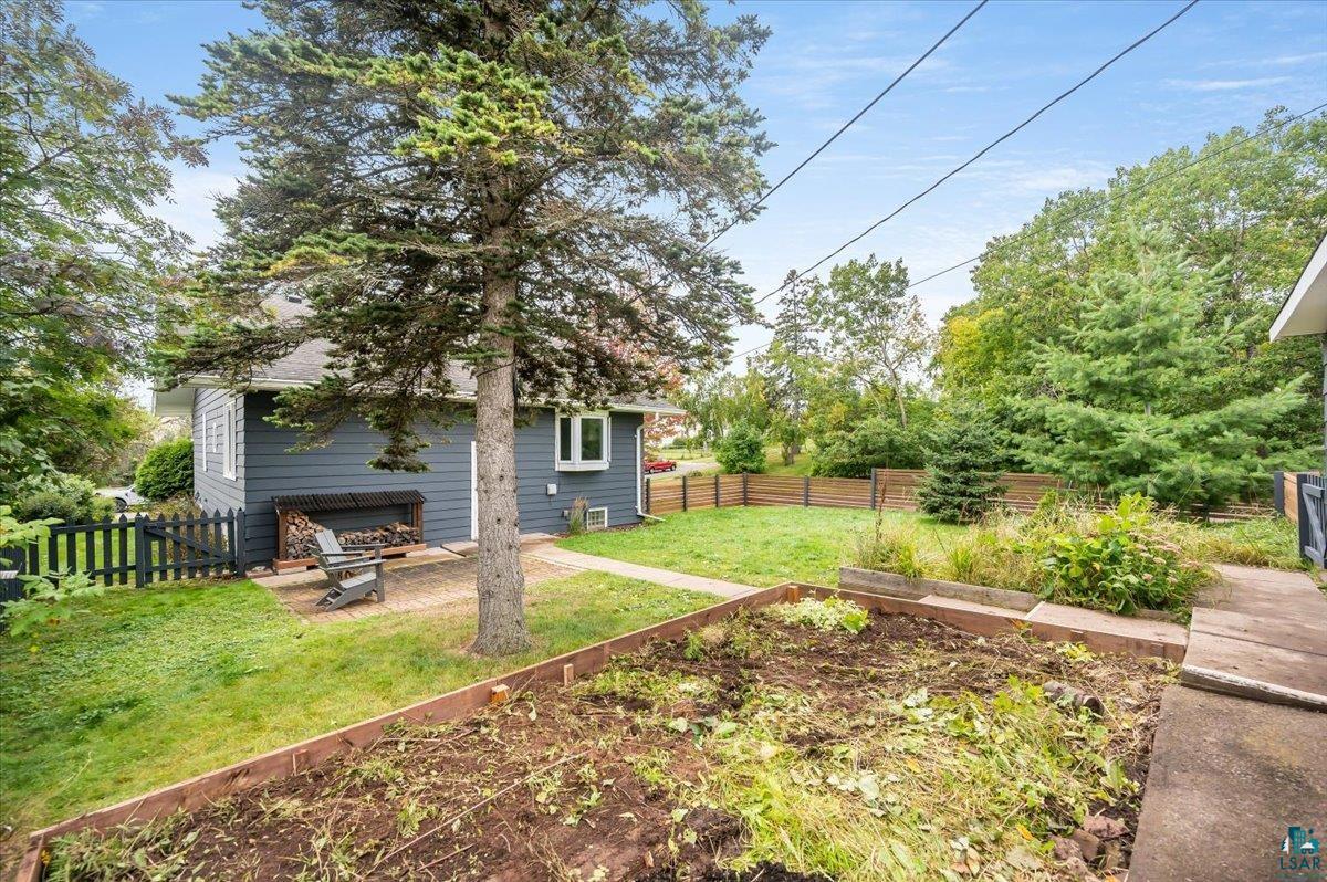 5401 Otsego Street Duluth, MN 55804 - Photo 27 of 36 Spacious backyard featuring a large tree, a raised garden bed, and a gravel patio area