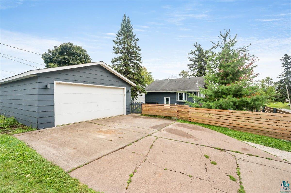 5401 Otsego Street Duluth, MN 55804 - Photo 28 of 36 Detached garage with horizontal siding, a white overhead door, and exterior sconce lighting
