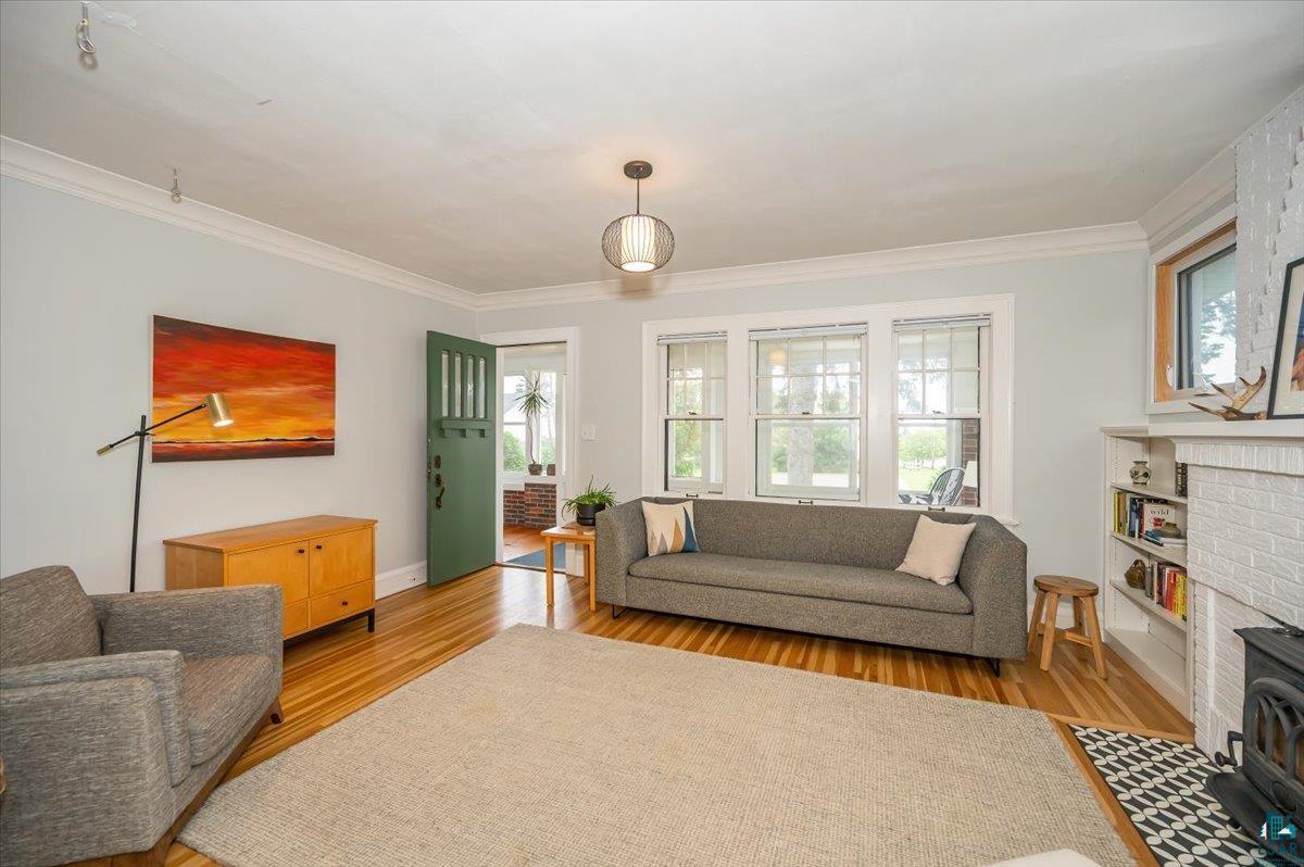 5401 Otsego Street Duluth, MN 55804 - Photo 6 of 36 Living room featuring wood-finish flooring, white crown molding, and a built-in bookshelf beside a white brick fireplace