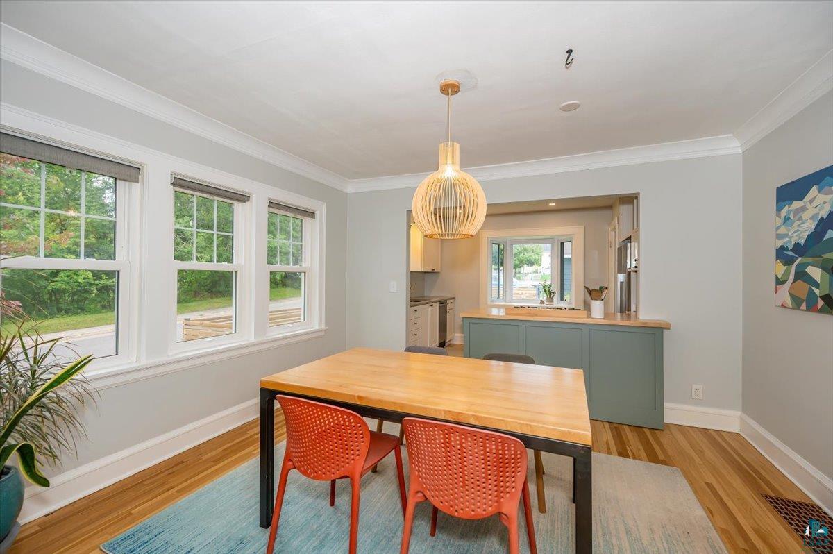 5401 Otsego Street Duluth, MN 55804 - Photo 7 of 36 Dining space featuring wood-finish flooring, crown molding, and a modern pendant light fixture