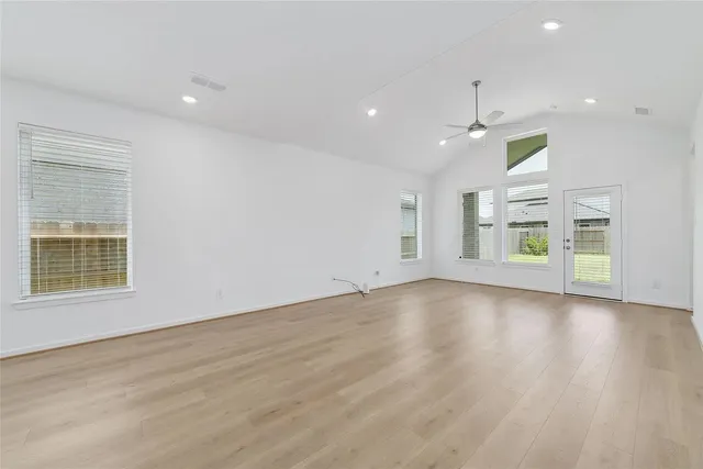 an empty room with wooden floor and windows