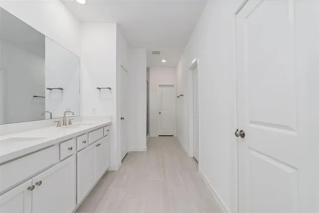 a spacious bathroom with a double vanity sink a mirror and a bathtub
