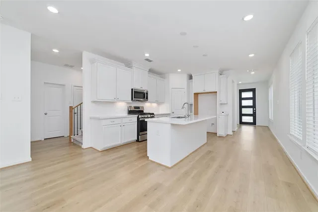 a large kitchen with stainless steel appliances a large counter top a stove and a refrigerator