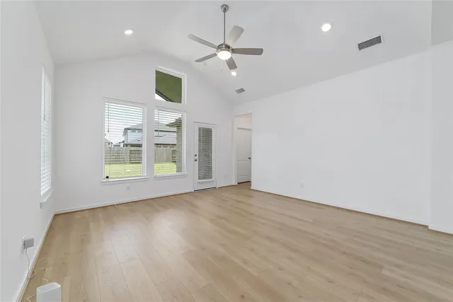 a view of an empty room with window and wooden floor