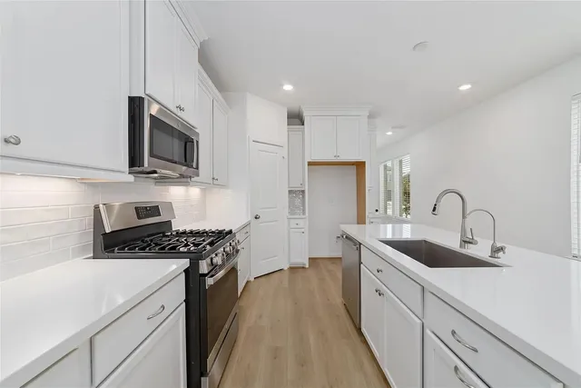a kitchen with kitchen island a sink appliances and cabinets