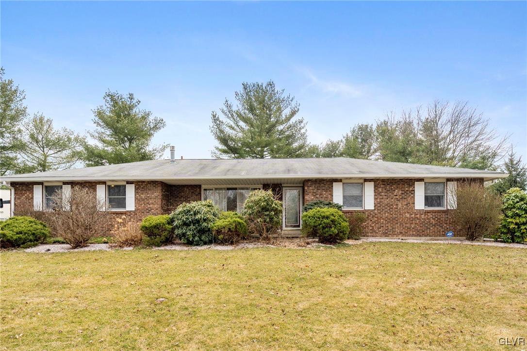 a front view of house with yard and trees in the background