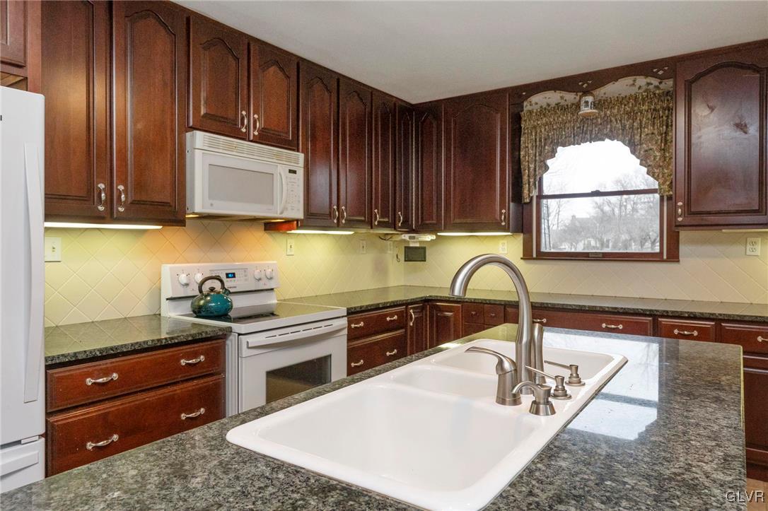 7058 Limerick Square Bethlehem, PA 18017 - Photo 12 of 30 a kitchen with stainless steel appliances granite countertop a sink a stove and cabinets