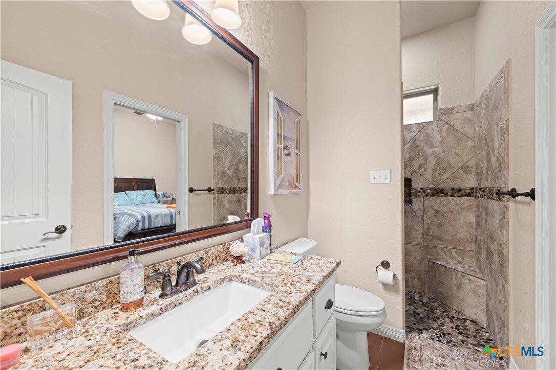 2649 Bowles Ranch Road Belton, TX 76513 - Photo 28 of 36 a bathroom with a granite countertop sink a large mirror and toilet