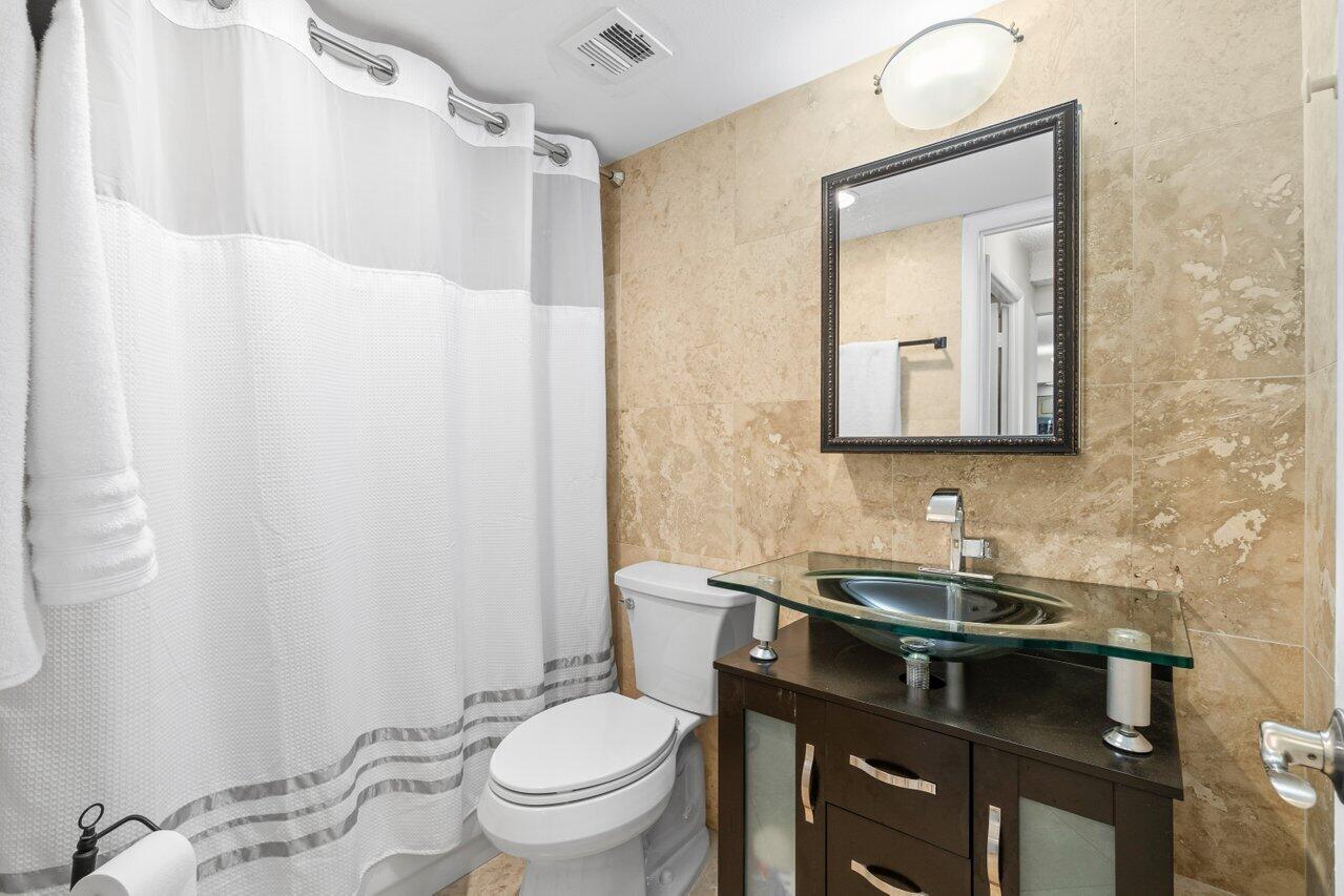 4511 South Ocean Boulevard, Unit 106 Highland Beach, FL 33487 - Photo 14 of 37 a bathroom with a sink a toilet and a mirror