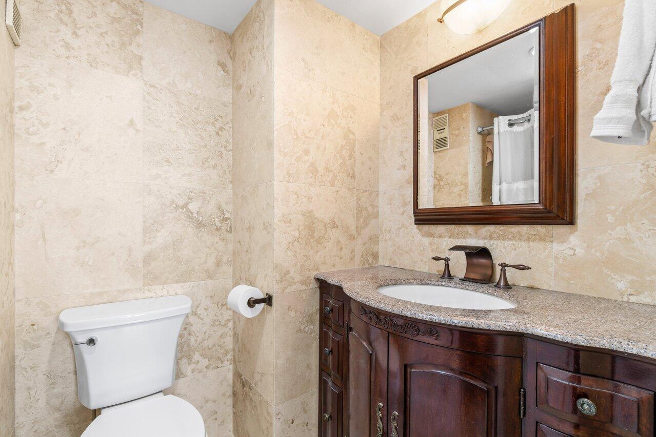 4511 South Ocean Boulevard, Unit 106 Highland Beach, FL 33487 - Photo 15 of 37 a bathroom with a toilet sink and mirror