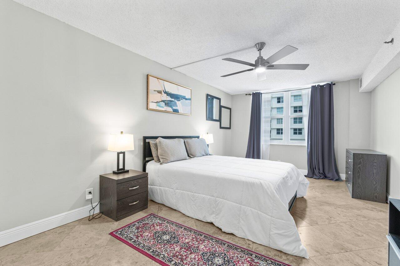 4511 South Ocean Boulevard, Unit 106 Highland Beach, FL 33487 - Photo 16 of 37 a bedroom with a large bed and a chandelier