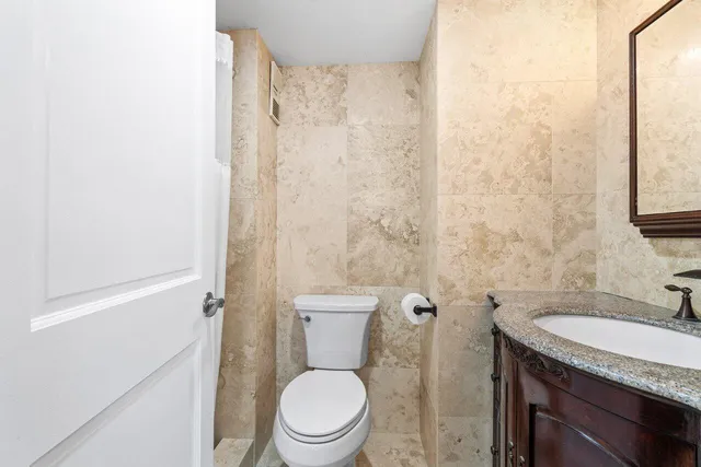 a bathroom with a granite countertop toilet a sink and a mirror