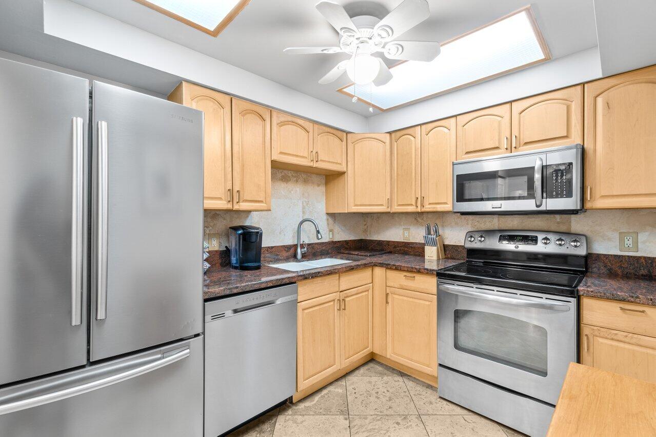 4511 South Ocean Boulevard, Unit 106 Highland Beach, FL 33487 - Photo 8 of 37 a kitchen with stainless steel appliances granite countertop white cabinets a sink a stove a refrigerator with grey cabinets