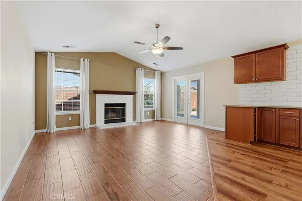 a view of an empty room with wooden floor fireplace and a window