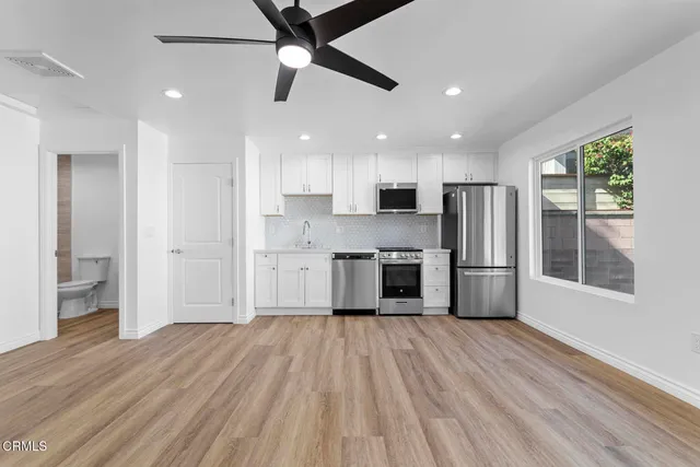 a kitchen with stainless steel appliances a refrigerator a sink a stove and white cabinets