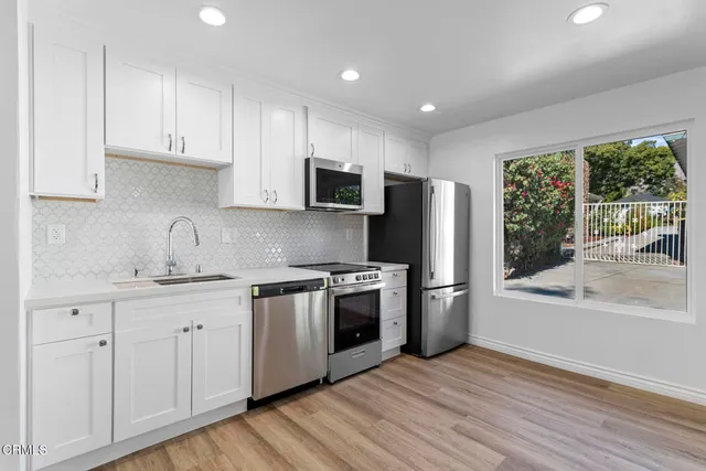 a kitchen with stainless steel appliances granite countertop a refrigerator a sink dishwasher a stove and a wooden floors