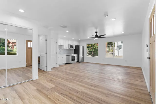 an empty room with wooden floor and windows
