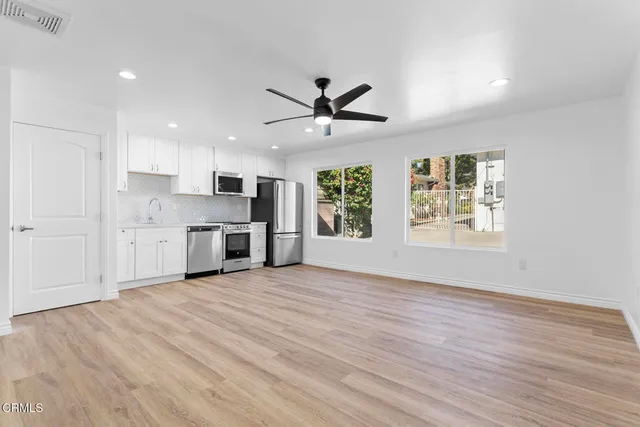 a view of a kitchen with a stove cabinets a ceiling fan and wooden floor