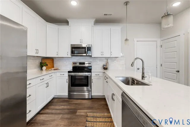 a kitchen with stainless steel appliances granite countertop a white stove top oven a sink and dishwasher with wooden floor