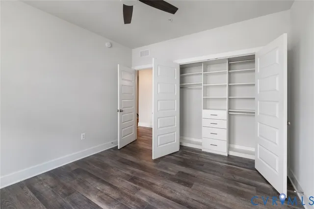 an empty room with walk in closet and wooden floor