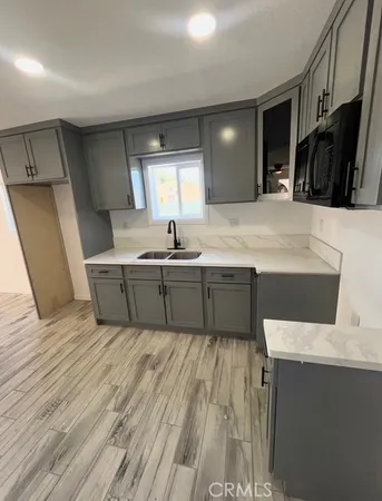 a large kitchen with stainless steel appliances a sink window and cabinets