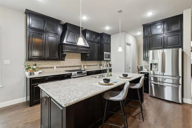 a kitchen with kitchen island stainless steel appliances a sink stove and refrigerator