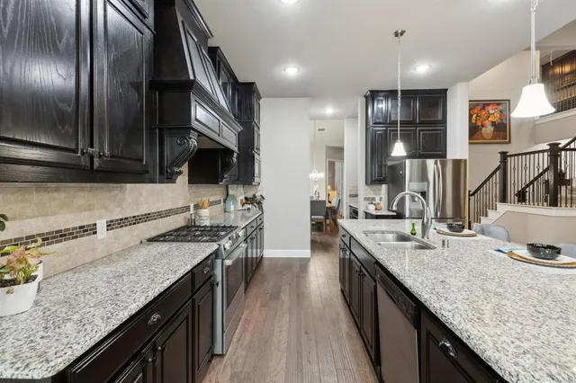 a kitchen with granite countertop stainless steel appliances a sink stove top oven and cabinets