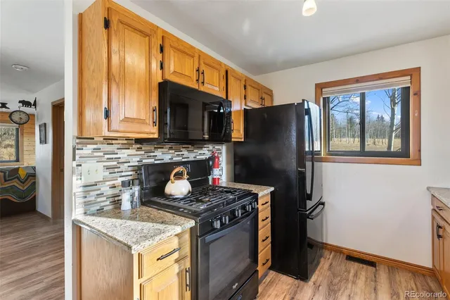 a kitchen with granite countertop a refrigerator stove and wooden floor