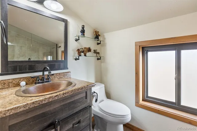 a bathroom with a granite countertop toilet sink and mirror