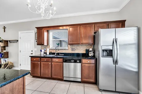 a kitchen with stainless steel appliances granite countertop a refrigerator a sink dishwasher a stove with wooden cabinets and floor