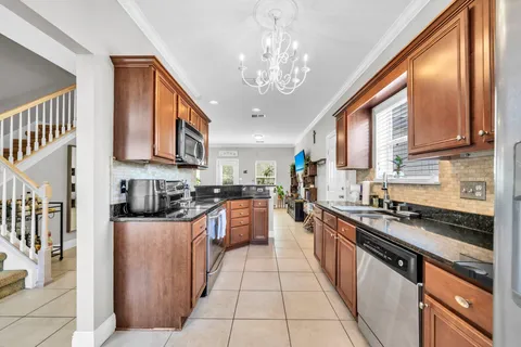 a kitchen with stainless steel appliances granite countertop a refrigerator a sink dishwasher a stove and white cabinets