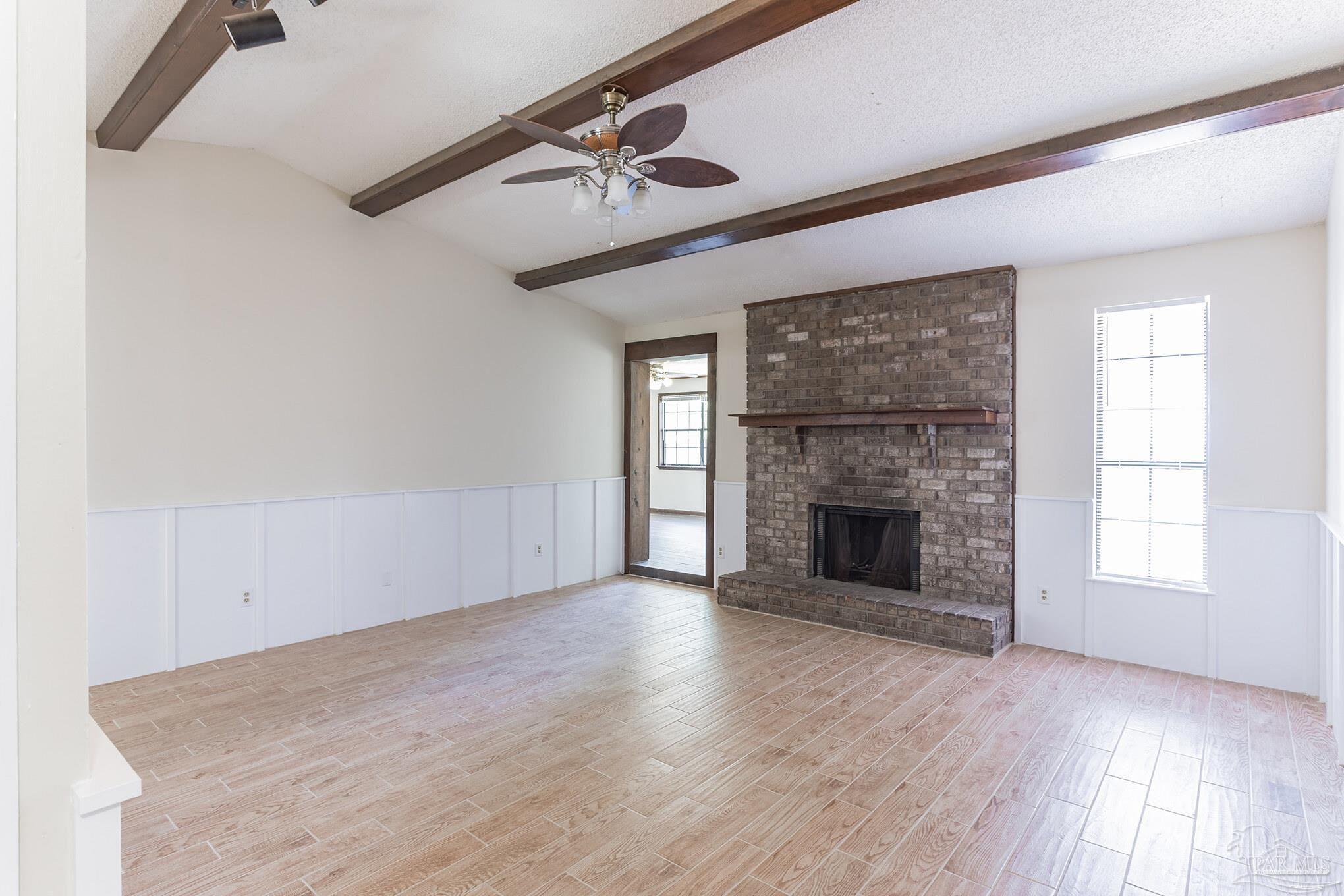 an empty room with windows fireplace and wooden floor